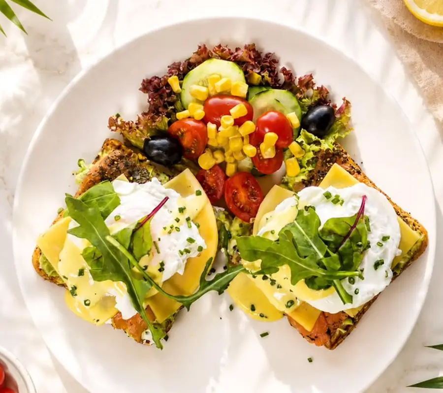 Toasts au saumon fumé, œufs pochés et sauce hollandaise, roquette et petite salade, vus de haut