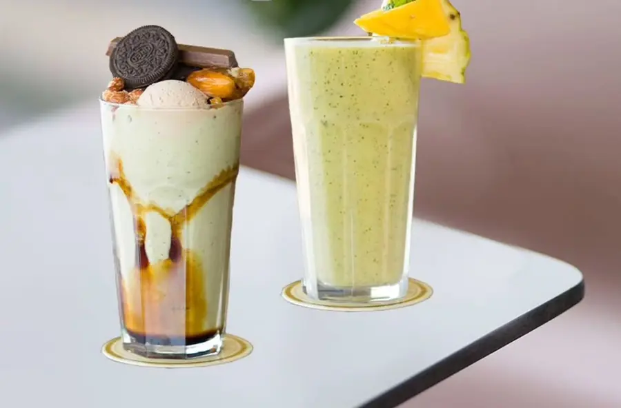 Deux milkshakes sur la table : l'un coulé de caramel et coiffé de biscuit, l'autre garni d'ananas frais
