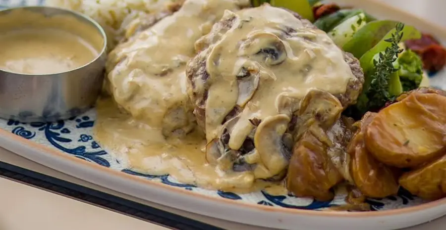 Viande hachée nappée d'une sauce crémeuse aux champignons, riz, légumes et pommes de terre sautées